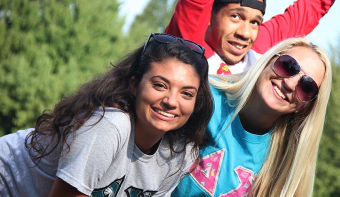 Three students look at and smile at the camera.